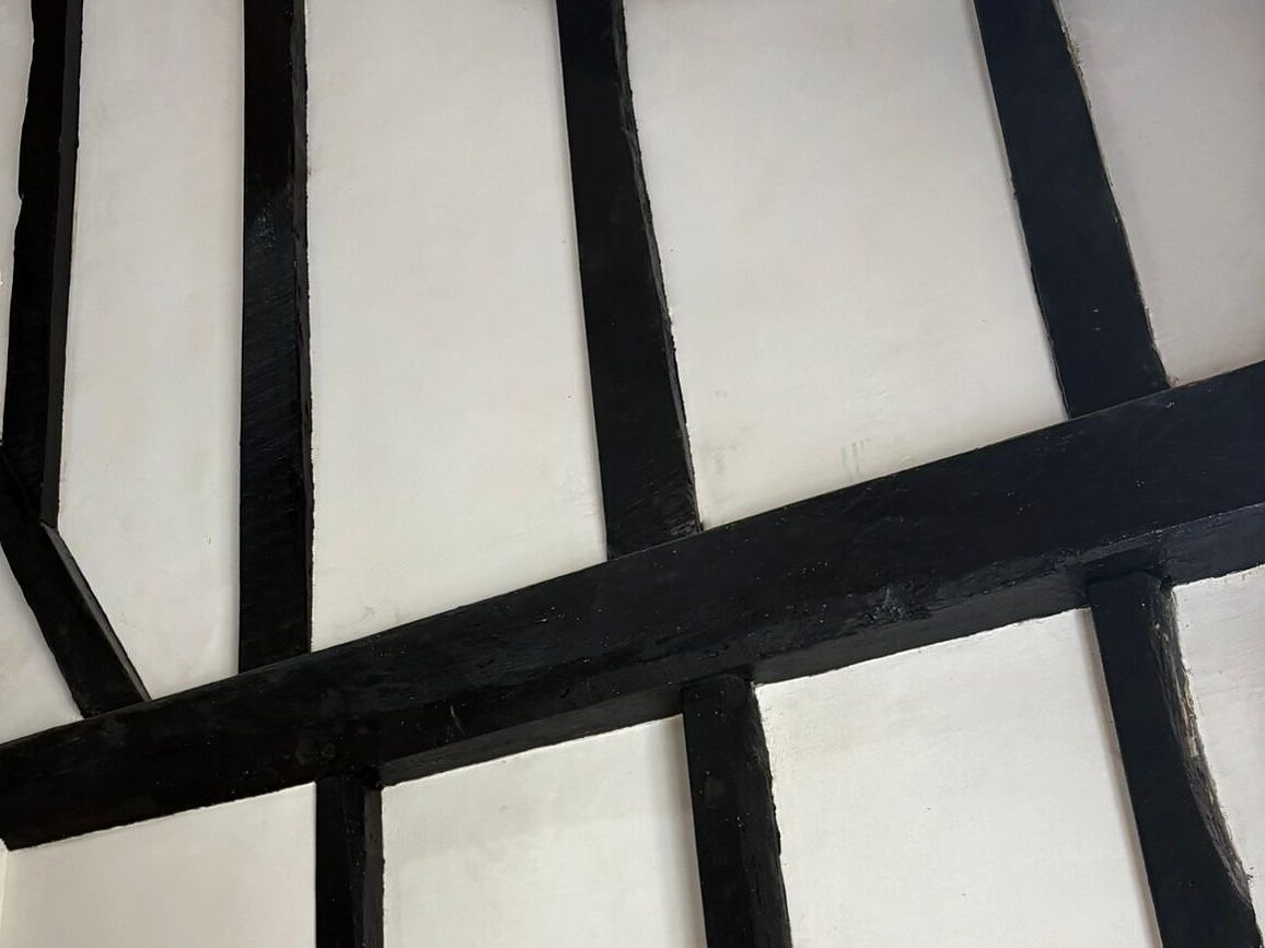 Timber-framed wall with smooth plaster panels between the black beams